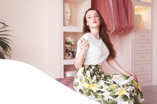 Beautiful young woman with bottle of perfume at home - pink dressing room