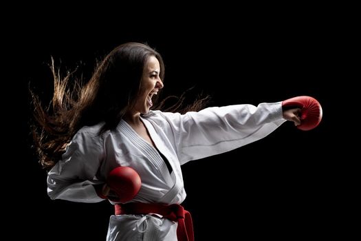 girl exercising karate punch and screaming against black background