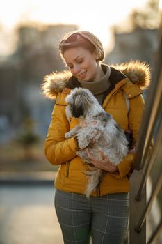 A smiling woman bonding with her cute Shih Tzu dog outdoors.