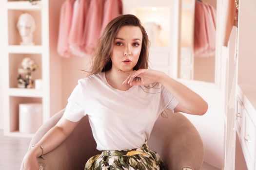 Happy young woman dressing up. Dressing room in pink colors. The concept of fashion and happiness