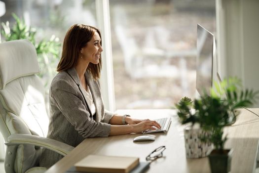 An attractive business woman sitting alone in her home office and working on computer.
