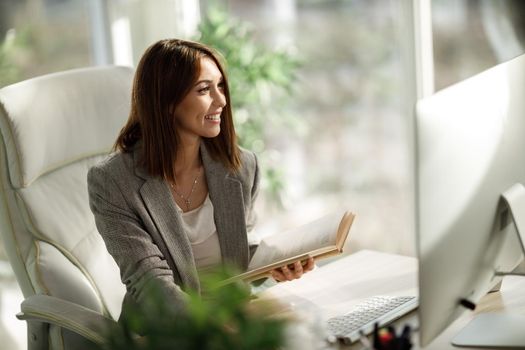 An attractive business woman sitting alone in her home office and working on computer.