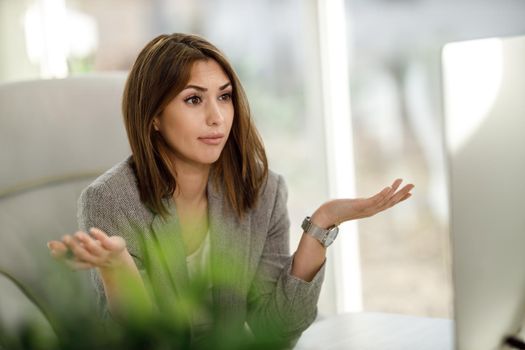 A young business woman looking stressed out while have a web conference at computer.
