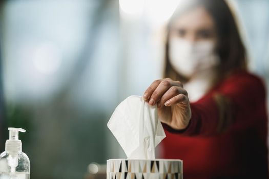 Close-up of female entrepreneur taking handkerchief from a box while working in the office during coronavirus pandemic.