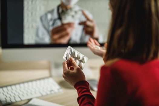 Unrecognizable woman holding a pills during a online consultation with a her doctor.