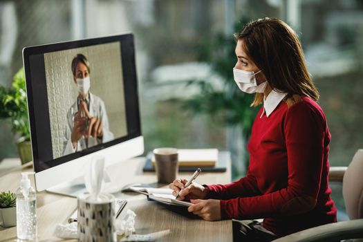 Shot of a young female patient writing notes during a video call with a her doctor on a computer.