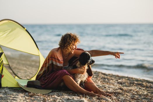 Young cheerful woman and her cute Cocker Spaniel dog having fun at the beach. 