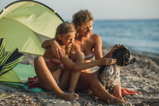 Young mom and her teen daughter spending day at the beach with their cute Cocker Spaniel dog. 