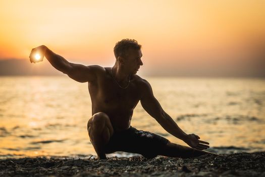 A handsome man doing tai chi chuan pose in sunset time on the beach.