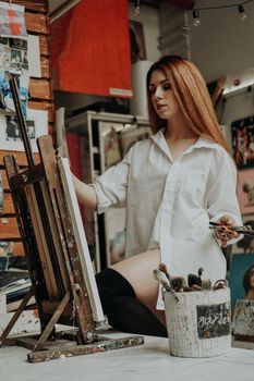 Portrait of female artist with brush in art workshop