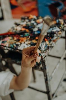 Closeup of female artist hand holding paintbrush at art workshop