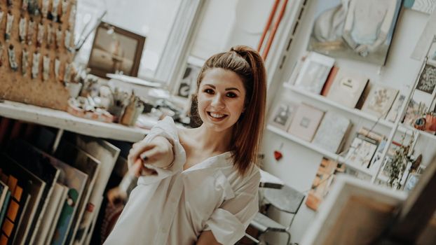 Portrait of happy smiling female artist with brush in art workshop. Selective focus. Vintage style photo