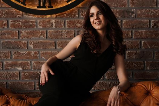 Young attractive woman under the clock, on brick wall background - loft style