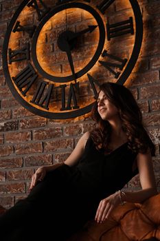Young attractive woman under the clock, on brick wall background - loft style