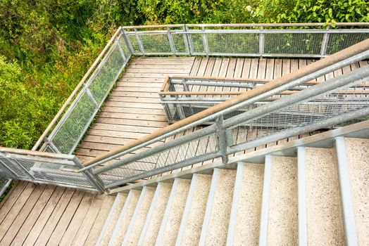 Stair and wooden deck with metal rails in a park.