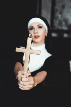 Nun holding a cross. The concept of religion. Young beautiful nun expels the devil