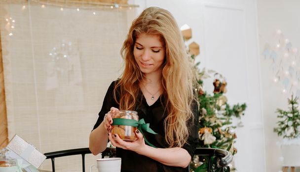 Happy young woman having eating christmas cookies in kitchen and smiling