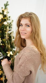 Beautiful young woman decorating a Christmas tree - soft colors preset