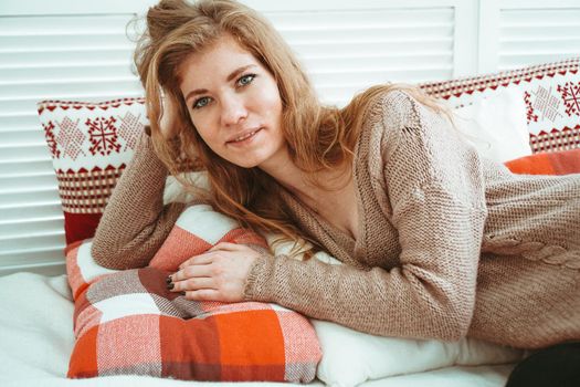 Morning, leisure, christmas, winter and people concept - happy young woman in bed at home bedroom