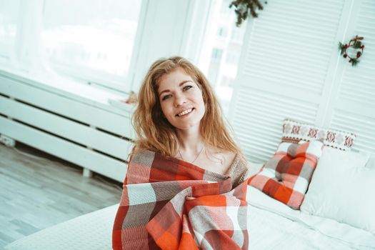 A beautiful laughing young Russian woman in a red plaid at home