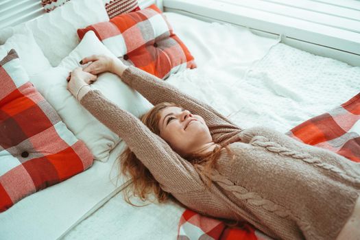 Happy woman lying on a bed with red and white check plaid and smiling