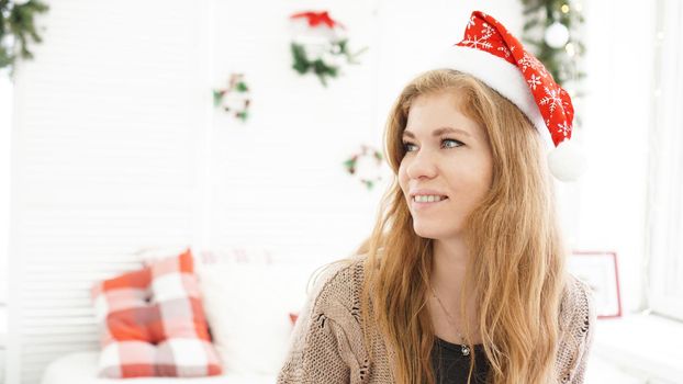 Portrait of attractive smiling woman in Christmas hat at nome - light cozy room