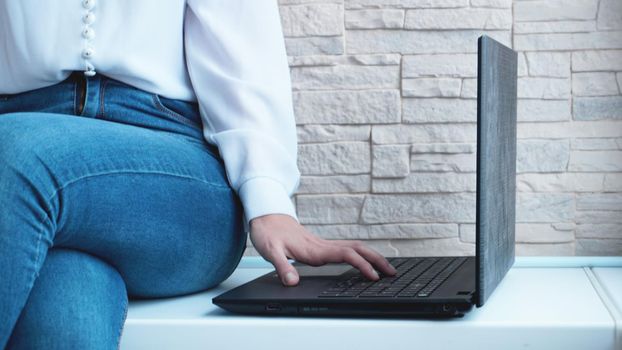 Woman working at home office hand on keyboard close up on brick wall background