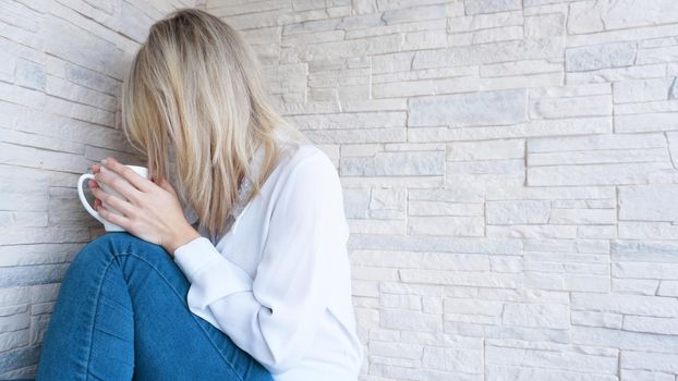 Sad or Depressed Young Beautiful Woman at home on brick wall background