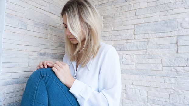 Sad or Depressed Young Beautiful Woman at home on brick wall background