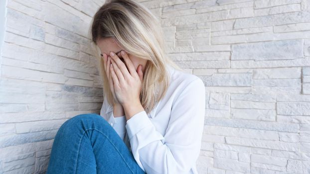 Sad or Depressed Young Beautiful Woman at home on brick wall background