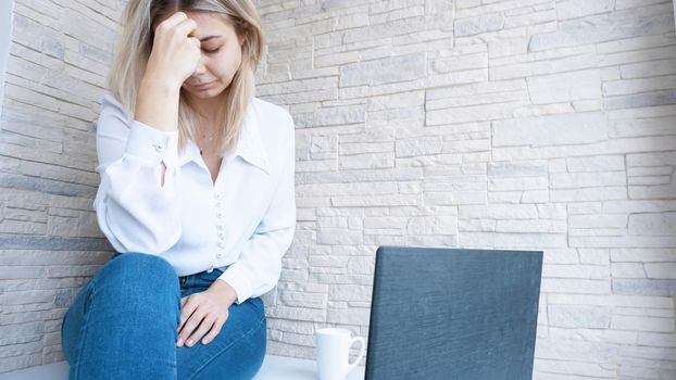 Woman looks at her laptop with a pained worried expression. Female employee is stressed out of work, touching aching head, reading email, solving a problem.