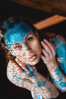 Portrait of beautiful woman with blue sparkles on her face. The concept of freaks and aliens. People are different from others. Individuality