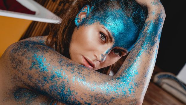 Portrait of beautiful woman with blue sparkles on her face. The concept of freaks and aliens. People are different from others. Individuality