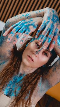 Portrait of beautiful woman with blue sparkles on her face. The concept of freaks and aliens. People are different from others. Individuality