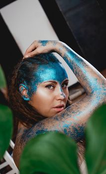 Portrait of a beautiful woman posing like in the wild forest. Woman with blue sparkles on her face. People are different from others. Individuality