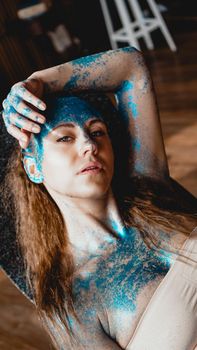 Portrait of beautiful woman with blue sparkles on her face. The concept of freaks and aliens. People are different from others. Individuality