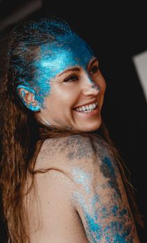 Portrait of beautiful happy woman with blue sparkles on her face. The concept of freaks and aliens. People are different from others. Individuality