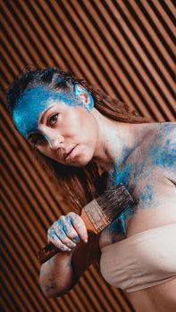 Portrait of beautiful girl with blue facial bodyart with sequins. The artist draws body art on herself