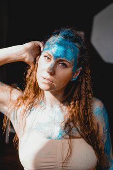 Portrait of beautiful woman with blue sparkles on her face. The concept of freaks and aliens. People are different from others. Individuality