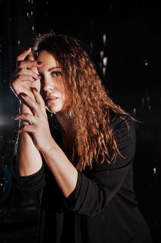 Wet beautiful woman in a black jacket under the falling drops of rain - photo in studio