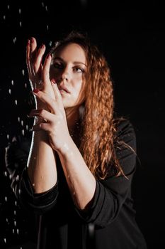 Wet beautiful woman in a black jacket under the falling drops of rain - photo in studio