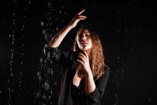 Wet beautiful woman in a black jacket under the falling drops of rain - photo in studio