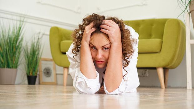 Stress young woman sitting and hold her head on wooden floor. Sexy female girl headache