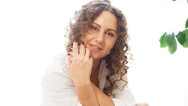 Portrait of a beautiful woman sitting at home with plants and smiling at camera. Happy morning - sunny day