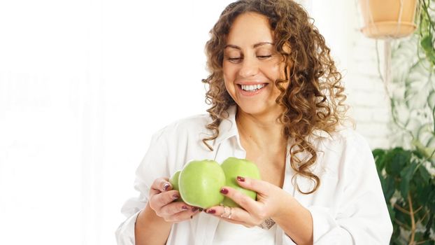 Senior happy woman with curly hair with green apples. Diet. Healthy lifestyle.