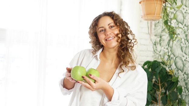 Senior happy woman with curly hair with green apples. Diet. Healthy lifestyle.
