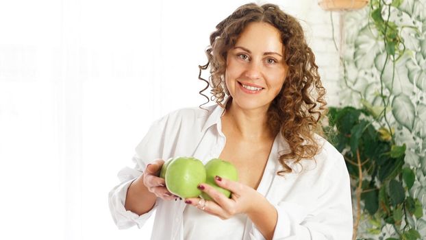 Senior happy woman with curly hair with green apples. Diet. Healthy lifestyle.