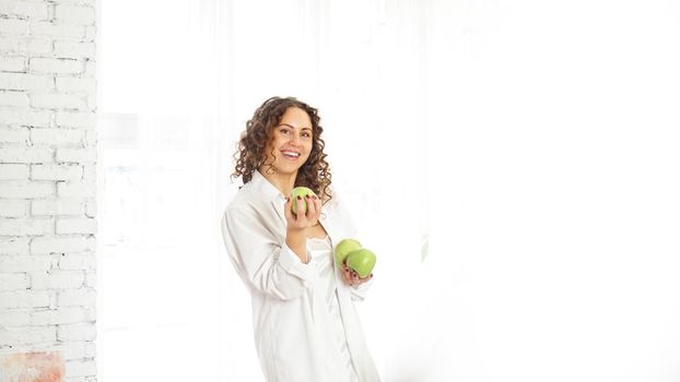 Senior happy woman with curly hair with green apples. Diet. Healthy lifestyle.