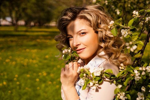 Romantic young woman in the spring garden among apple blossom. Beautiful woman, happy spring