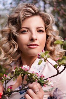 Romantic young woman in the spring garden among apple blossom. Beautiful woman, happy spring
